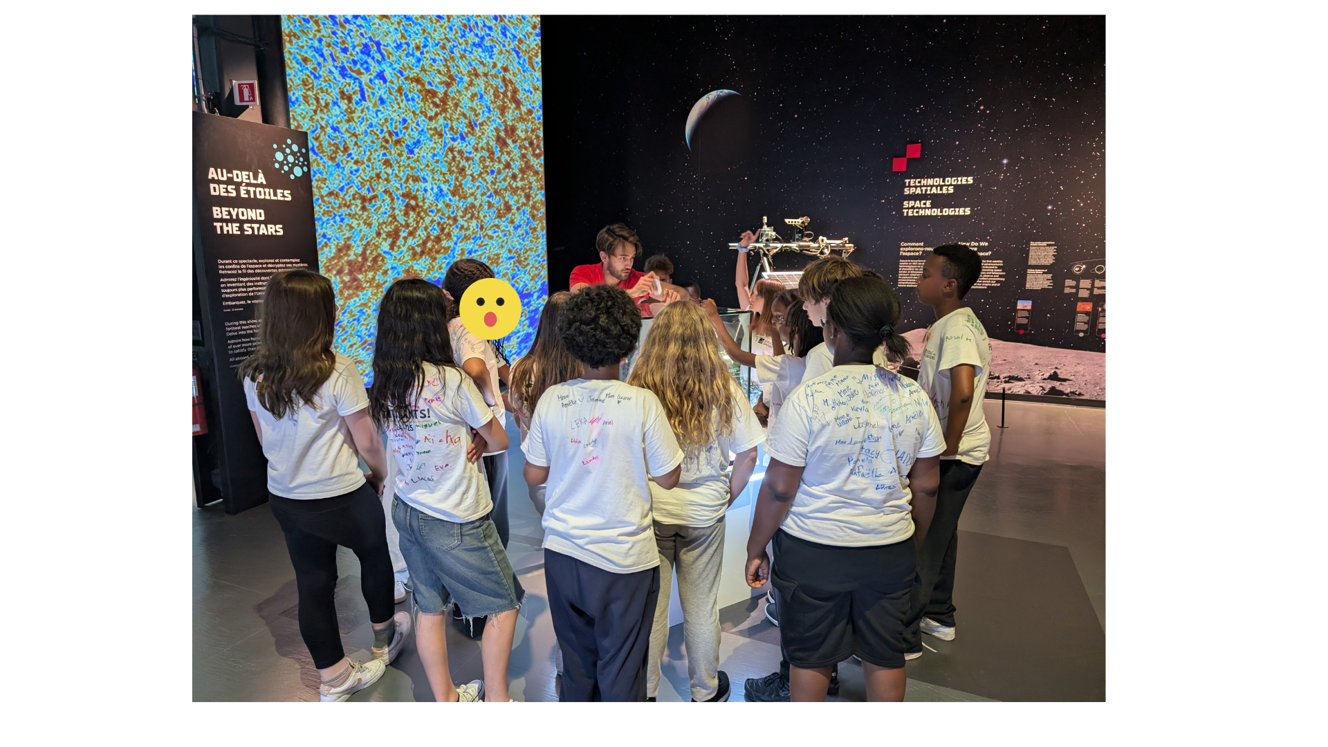 Groupe d'élèves avec un animateur devant un tableau représentant des étoiles.